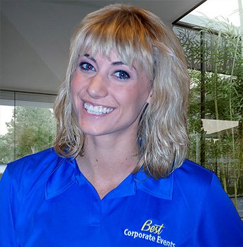 A blonde woman in a blue shirt smiling.