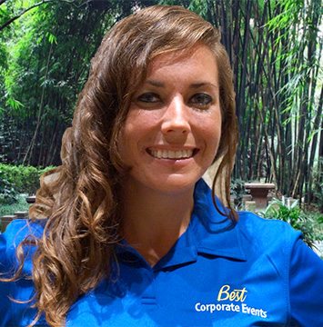 A woman in a blue shirt standing in front of bamboo.
