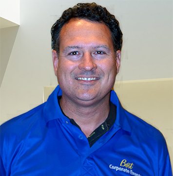 A man in a blue shirt smiling for the camera.