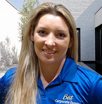 A woman in a blue shirt standing in front of a building.