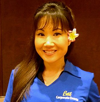 A woman in a blue shirt with a flower in her hair.