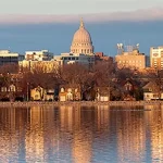 The city of milwaukee is reflected in a body of water.