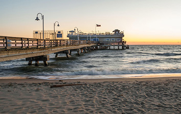 A pier on a beach at sunset.