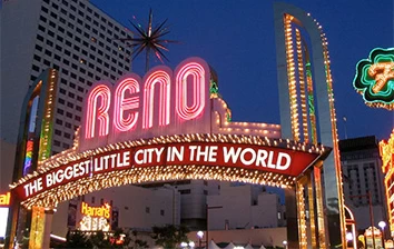A neon sign that says reno the biggest city in the world.