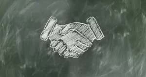 A handshake drawn in chalk on a blackboard.