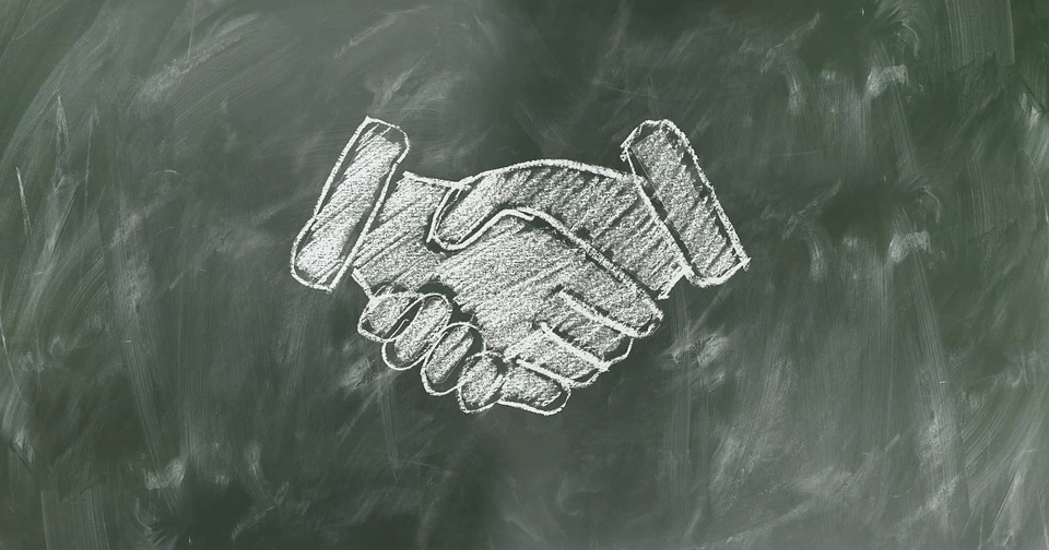 A handshake drawn in chalk on a blackboard.