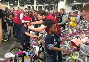 Best Corporate Events featuring a group of people standing around a group of children with bicycles.