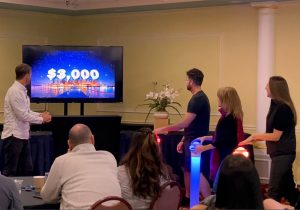 A group of people standing in front of a tv playing a game.