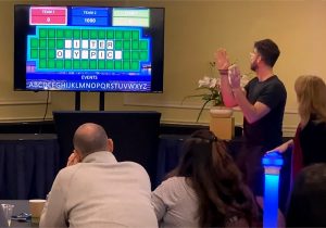 A group of people in front of a tv playing a game of monopoly.