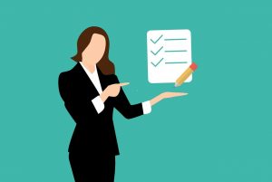 A woman in a business suit, pointing to a checklist as a team building guide.