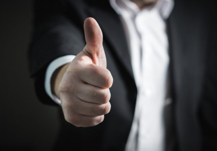 A person in a suit gives a thumbs-up gesture, embodying the spirit of how to keep employees happy.