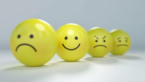 Four yellow emoticon balls are displayed in a row showing different expressions: sad, happy, angry, and worried. This playful arrangement aims to boost morale by making emotions more relatable and engaging.
