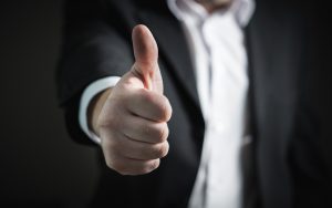 A person in a suit giving a thumbs-up gesture, demonstrating how to keep employees happy.