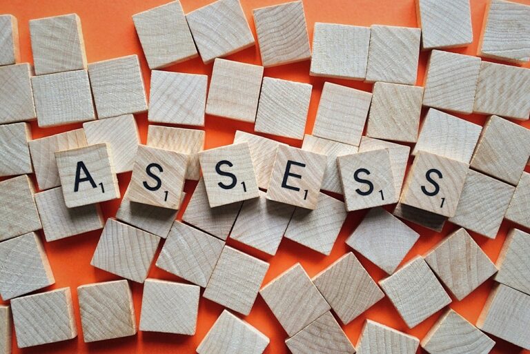 Scrabble tiles on a wooden surface spell out the word "ASSESS" amid scattered blank tiles, highlighting the importance of a leadership potential assessment.