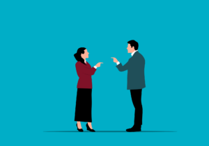 Illustration of a woman and a man standing and pointing at each other, appearing to have a disagreement, with a plain blue background—depicting how to deal with difficult people at work.