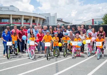 A group of people posing for a photo with bicycles as part of a CSR initiative.