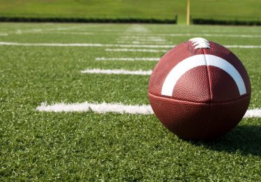 Discover valuable business lessons from the world of sports as you observe a football resting on a vibrant field.