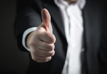 A person in a suit gives a thumbs-up gesture, embodying the spirit of how to keep employees happy.