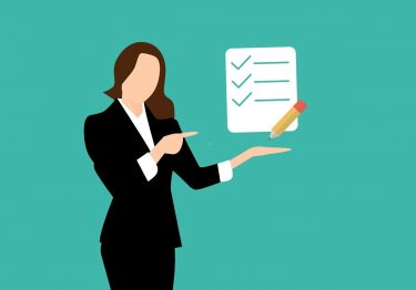 A woman in a business suit, pointing to a checklist as a team building guide.