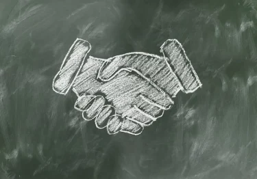 A handshake drawn in chalk on a blackboard.