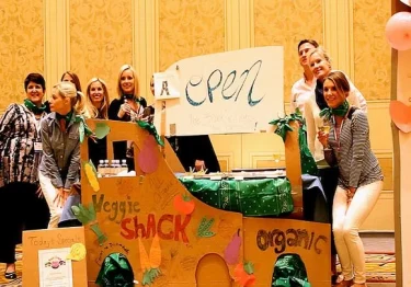 A group of people cooking in front of a cardboard sign.