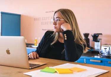 A woman sitting at a desk with a laptop, engaged in team building activities.