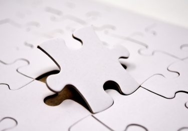 A white puzzle piece with a missing piece, symbolizing the importance of corporate team building and its valuable takeaways.