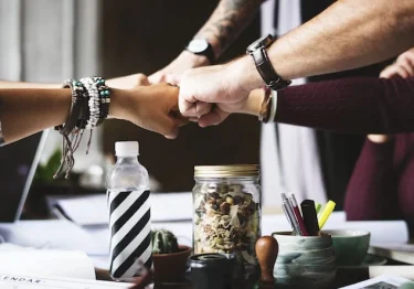 A group of people enjoying the benefits of collaboration, shaking hands at a table.