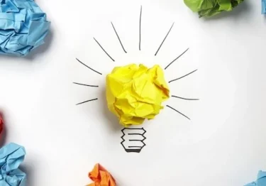 A light bulb surrounded by colored crumpled paper.
